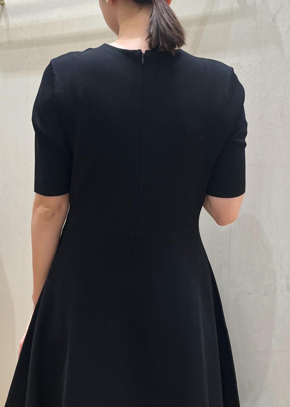 ブラック系のハンドバッグ、ブラック系のパンプス、ブルー系のワンピースを着用したレディースの冬コーディネートの8枚目の写真