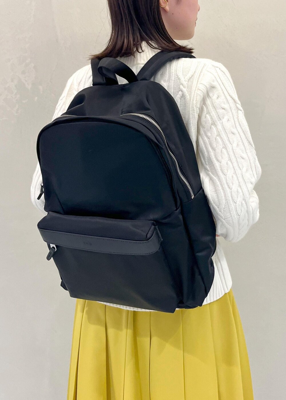 ブラウン系のブーツ、イエロー系のスカート、ブラック系のバックパック/リュックを着用したレディースの冬コーディネートの6枚目の写真