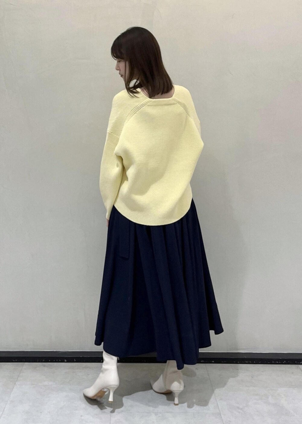 ホワイト系のハンドバッグ、ホワイト系のブーツ、ブルー系のスカートを着用したレディースの冬コーディネートの3枚目の写真