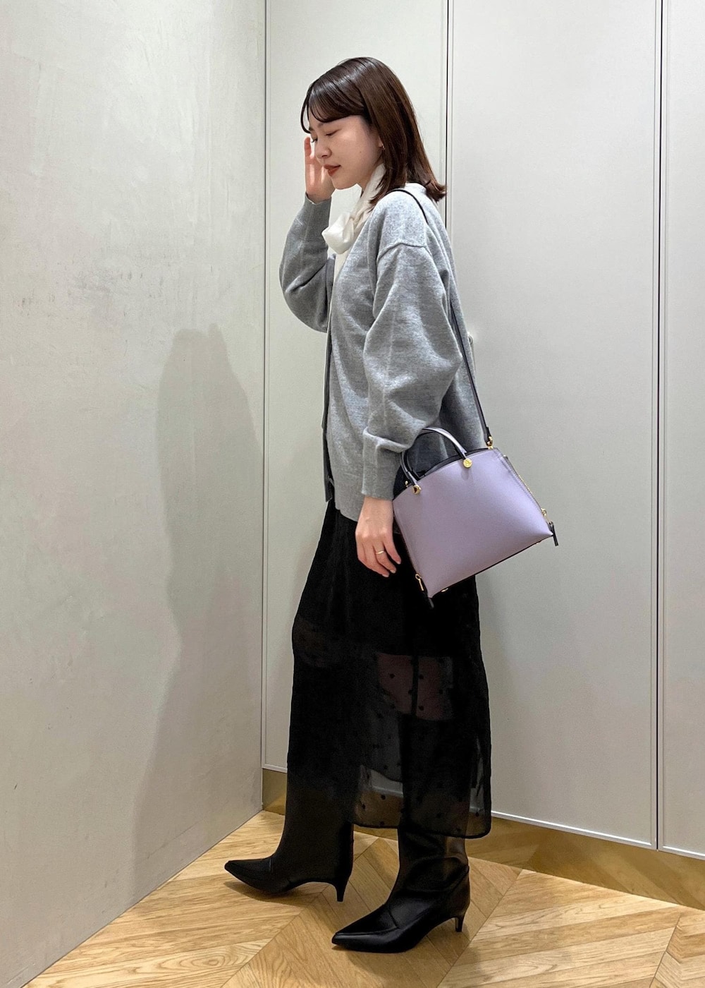 ブラック系のブーツ、ホワイト系のシャツ/ブラウス、グレー系のカーディガン/ボレロを着用したレディースの秋コーディネートの3枚目の写真