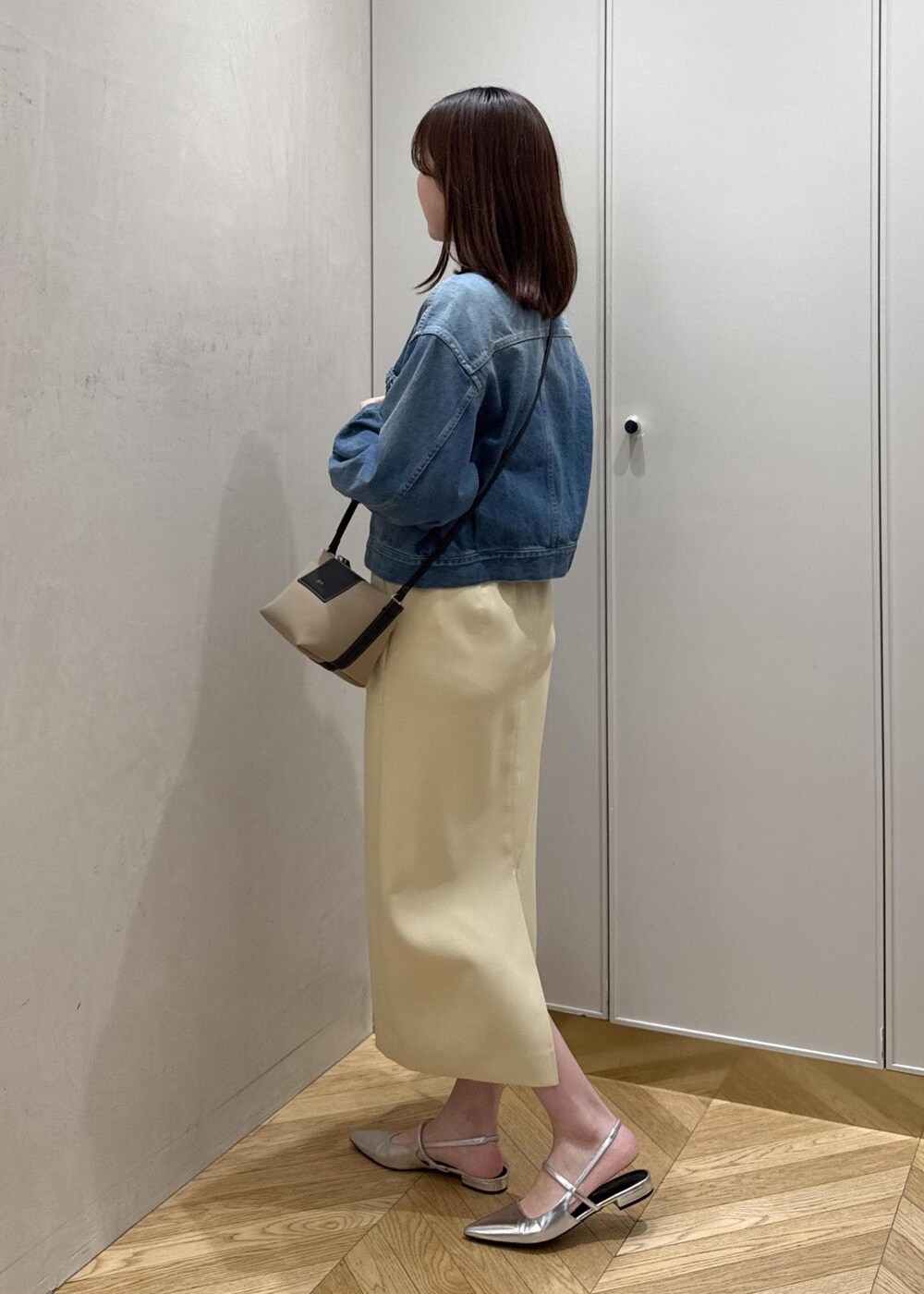 ベージュ系のショルダーバッグ、イエロー系のスカート、ブルー系のデニムジャケットを着用したレディースの春コーディネートの2枚目の写真