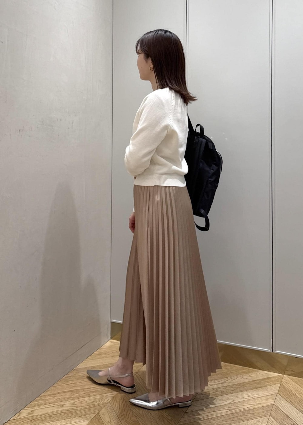 ブラック系のバックパック/リュック、ホワイト系のTシャツ/カットソー、ベージュ系のスカートを着用したレディースの春コーディネートの2枚目の写真