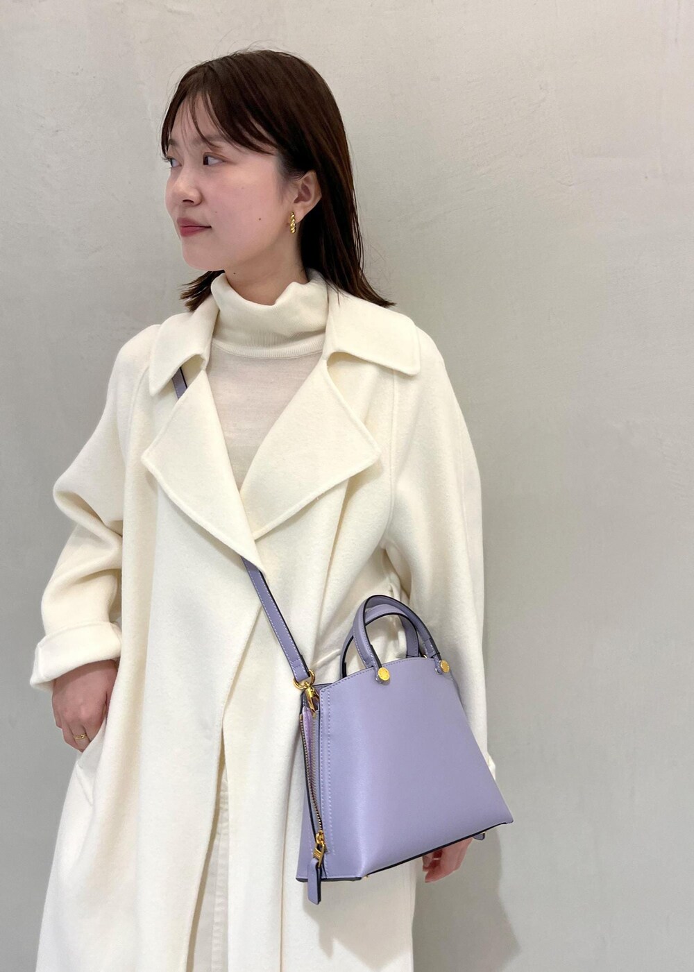 ブラック系のブーツ、ホワイト系のチェスターコート、ホワイト系のスカートを着用したレディースの秋コーディネートの4枚目の写真