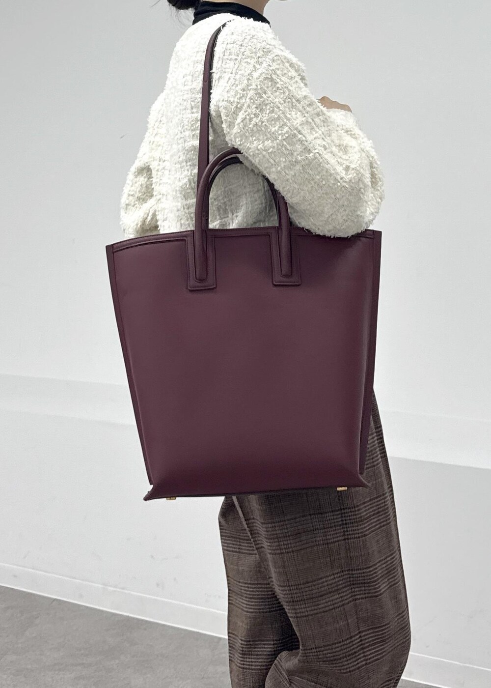 レッド系のトートバッグ、ブラウン系のブーツ、ブラック系のTシャツ/カットソーを着用したレディースの秋コーディネートの8枚目の写真