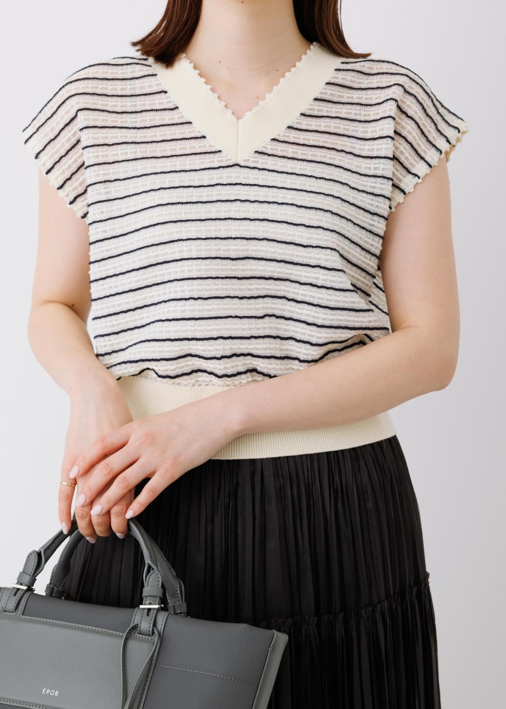 ブラック系のスカート、ホワイト系のニット/セーター、グレー系のトートバッグを着用したレディースの春コーディネートの4枚目の写真