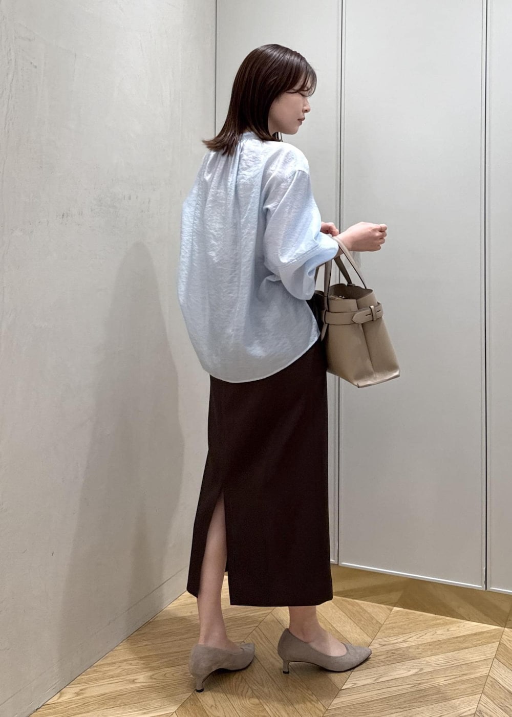 ブラウン系のスカート、ベージュ系のハンドバッグ、ブルー系のシャツ/ブラウスを着用したレディースの春コーディネートの3枚目の写真