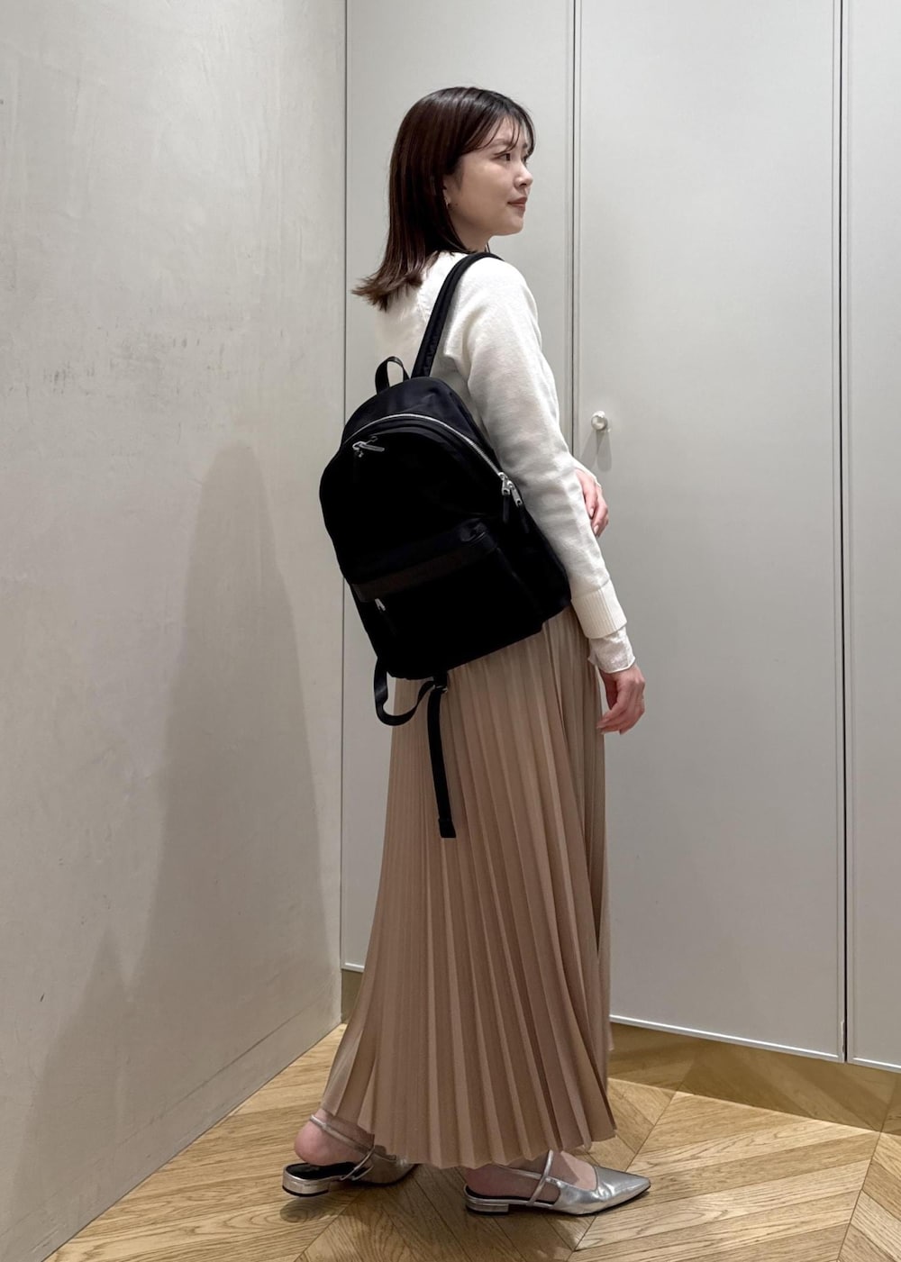 ブラック系のバックパック/リュック、ホワイト系のTシャツ/カットソー、ベージュ系のスカートを着用したレディースの春コーディネートの3枚目の写真