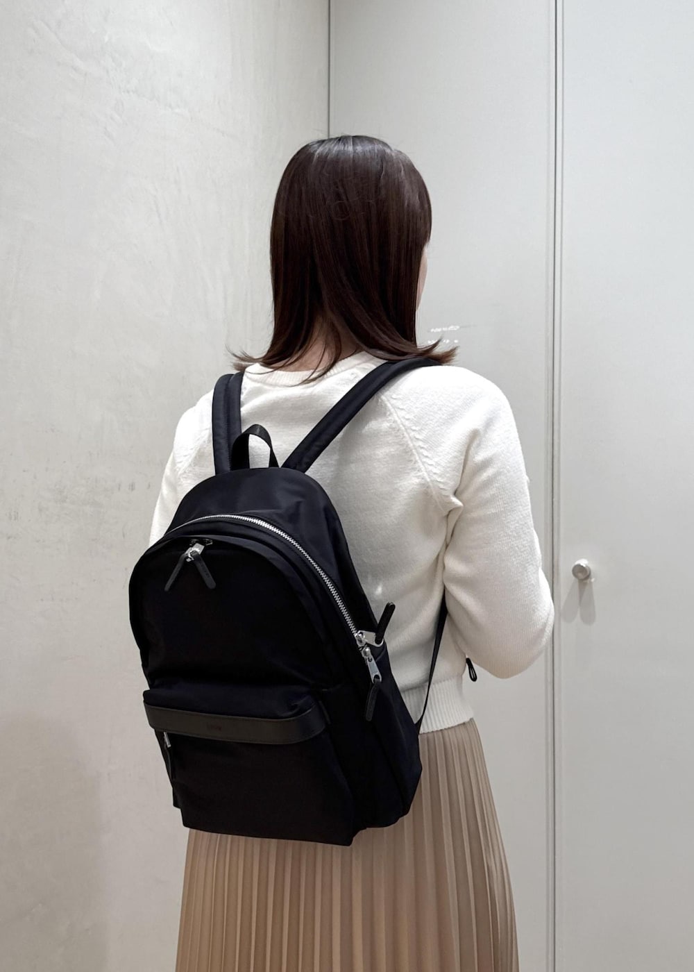ブラック系のバックパック/リュック、ホワイト系のTシャツ/カットソー、ベージュ系のスカートを着用したレディースの春コーディネートの8枚目の写真