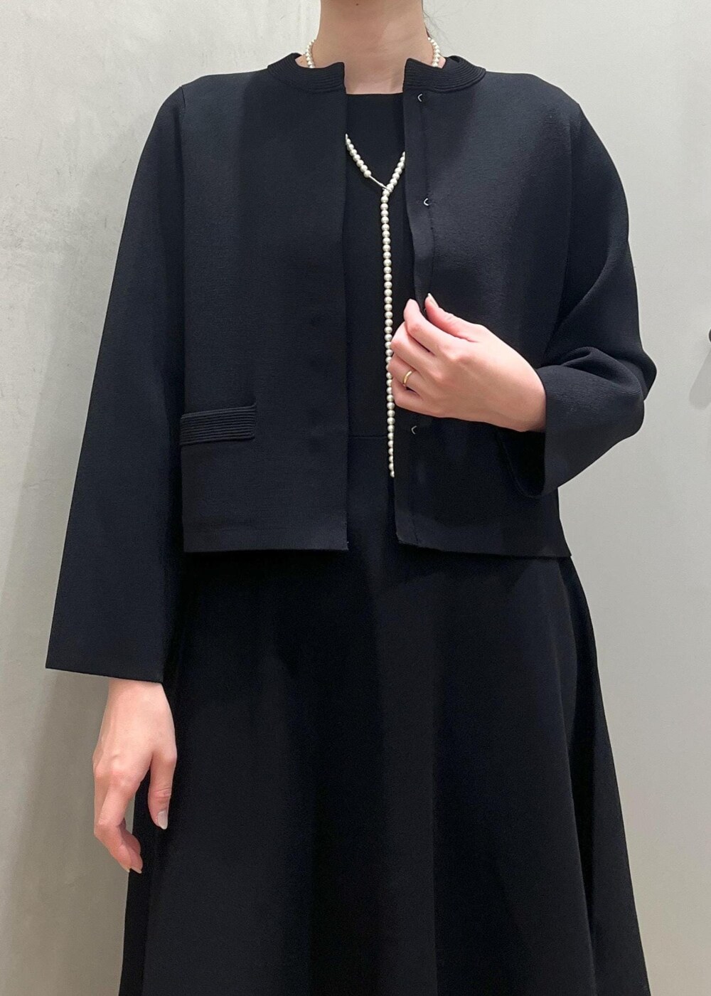 ブラック系のハンドバッグ、ブラック系のパンプス、ブルー系のワンピースを着用したレディースの冬コーディネートの4枚目の写真