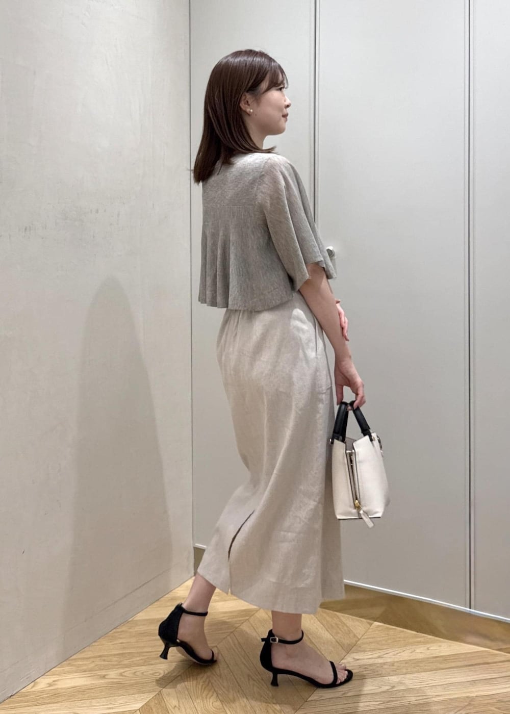 ホワイト系のハンドバッグ、ベージュ系のTシャツ/カットソー、ベージュ系のスカートを着用したレディースの夏コーディネートの3枚目の写真