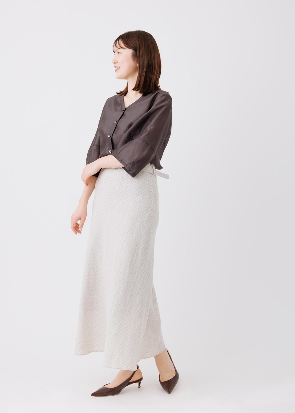 ベージュ系のスカート、ブラック系のシャツ/ブラウスを着用したレディースの春コーディネートの2枚目の写真