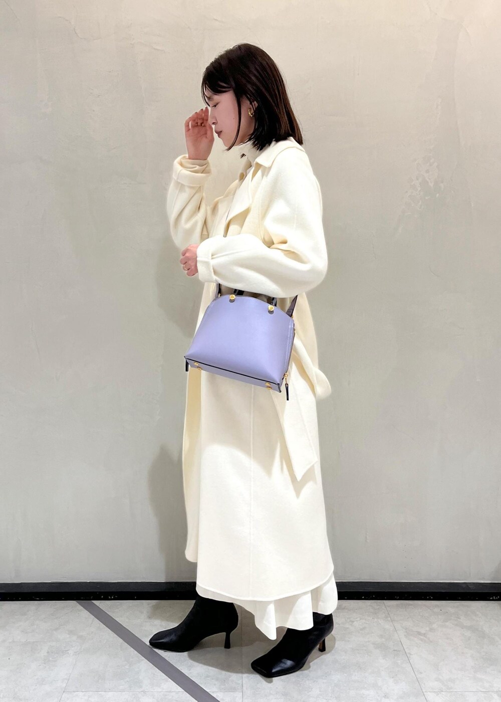 ブラック系のブーツ、ホワイト系のチェスターコート、ホワイト系のスカートを着用したレディースの秋コーディネートの2枚目の写真