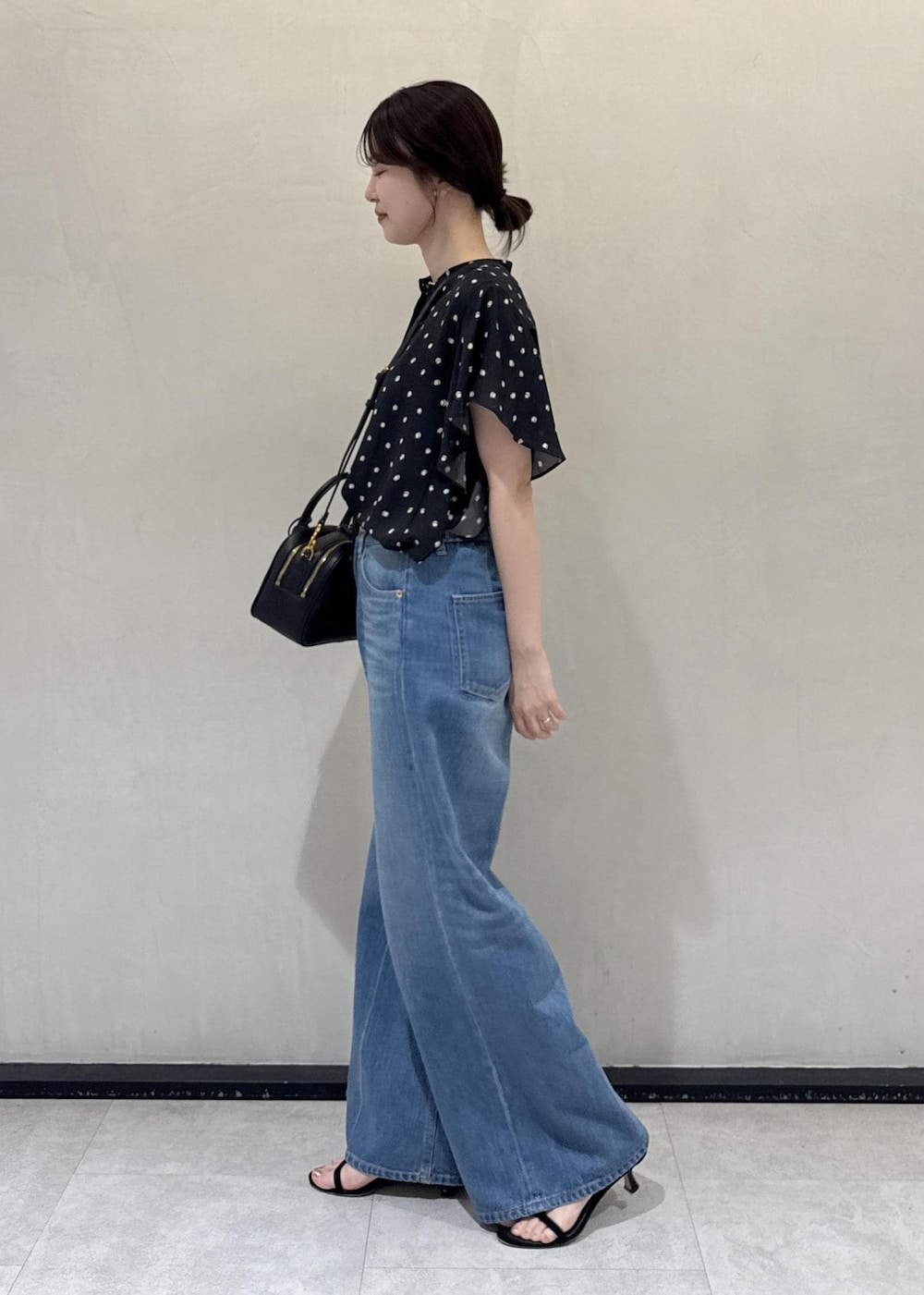 ブルー系のデニムパンツ、ブラック系のシャツ/ブラウス、ブラック系のハンドバッグを着用したレディースの夏コーディネートの2枚目の写真