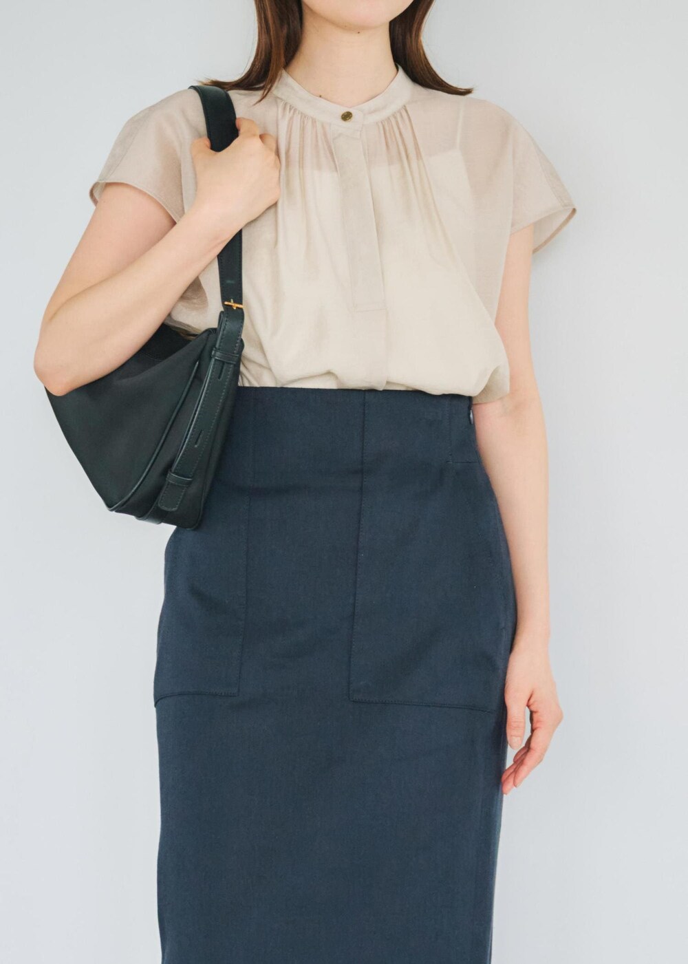 ブルー系のスカート、ブラック系のハンドバッグ、ベージュ系のシャツ/ブラウスを着用したレディースの春コーディネートの3枚目の写真