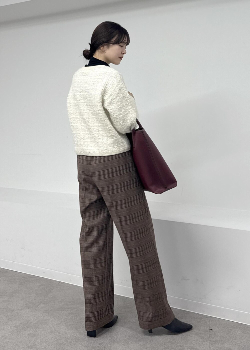 レッド系のトートバッグ、ブラウン系のブーツ、ブラック系のTシャツ/カットソーを着用したレディースの秋コーディネートの3枚目の写真