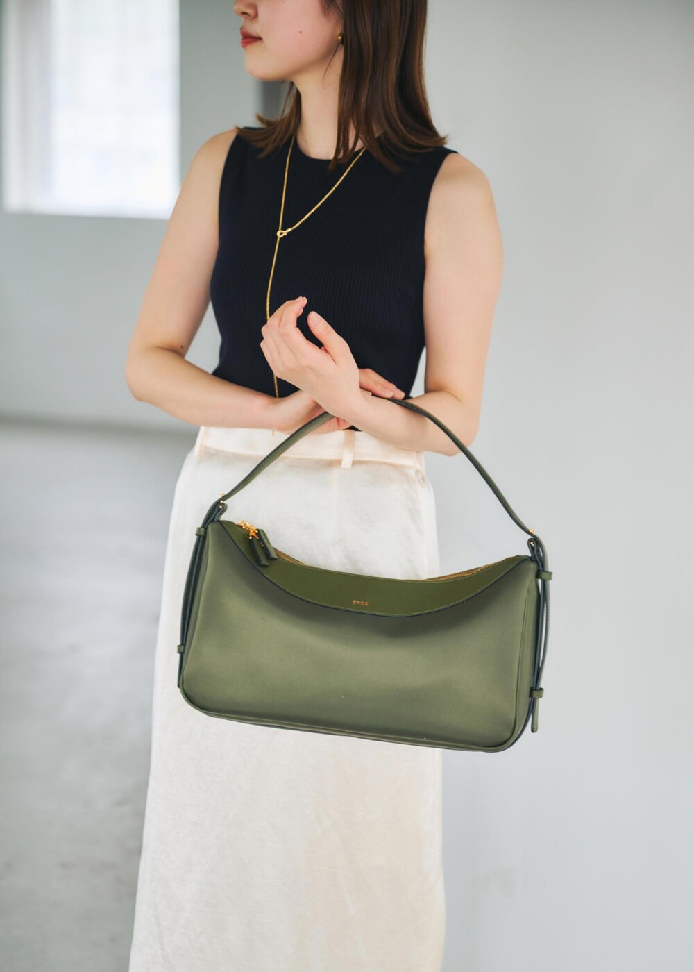 ブルー系のニット/セーター、グリーン系のハンドバッグ、ホワイト系のスカートを着用したレディースの春コーディネートの4枚目の写真