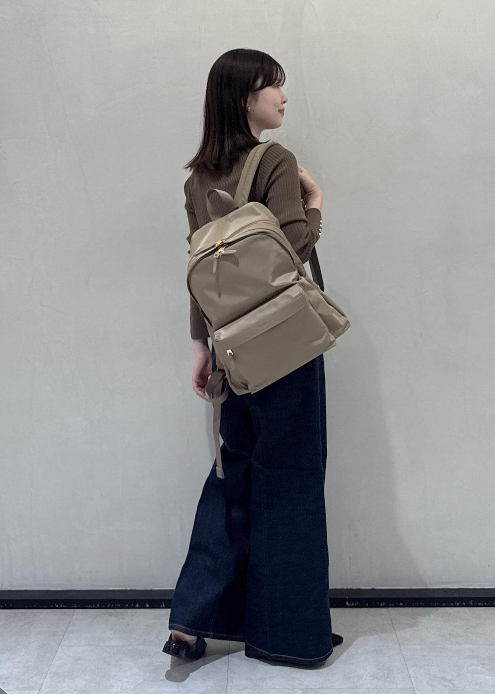ベージュ系のバックパック/リュック、ブルー系のデニムパンツ、ブラウン系のカーディガン/ボレロを着用したレディースの秋コーディネートの4枚目の写真