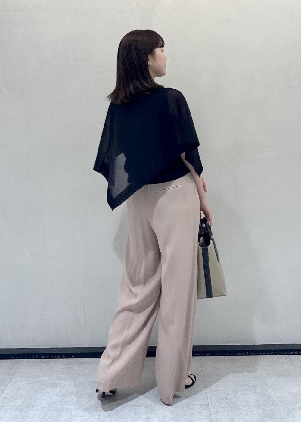 ベージュ系のトートバッグ、ベージュ系のその他パンツ、ブラック系のTシャツ/カットソーを着用したレディースの春コーディネートの4枚目の写真