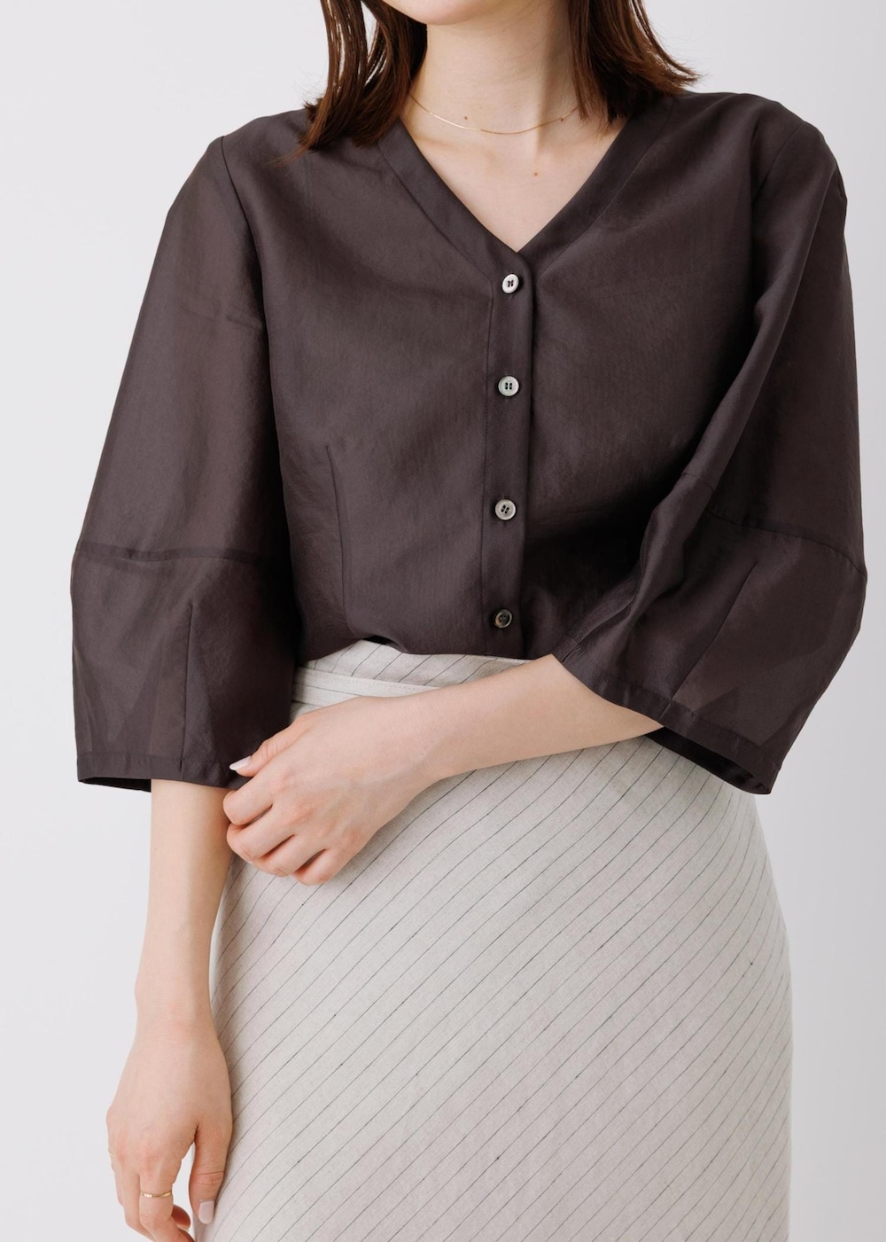 ベージュ系のスカート、ブラック系のシャツ/ブラウスを着用したレディースの春コーディネートの4枚目の写真