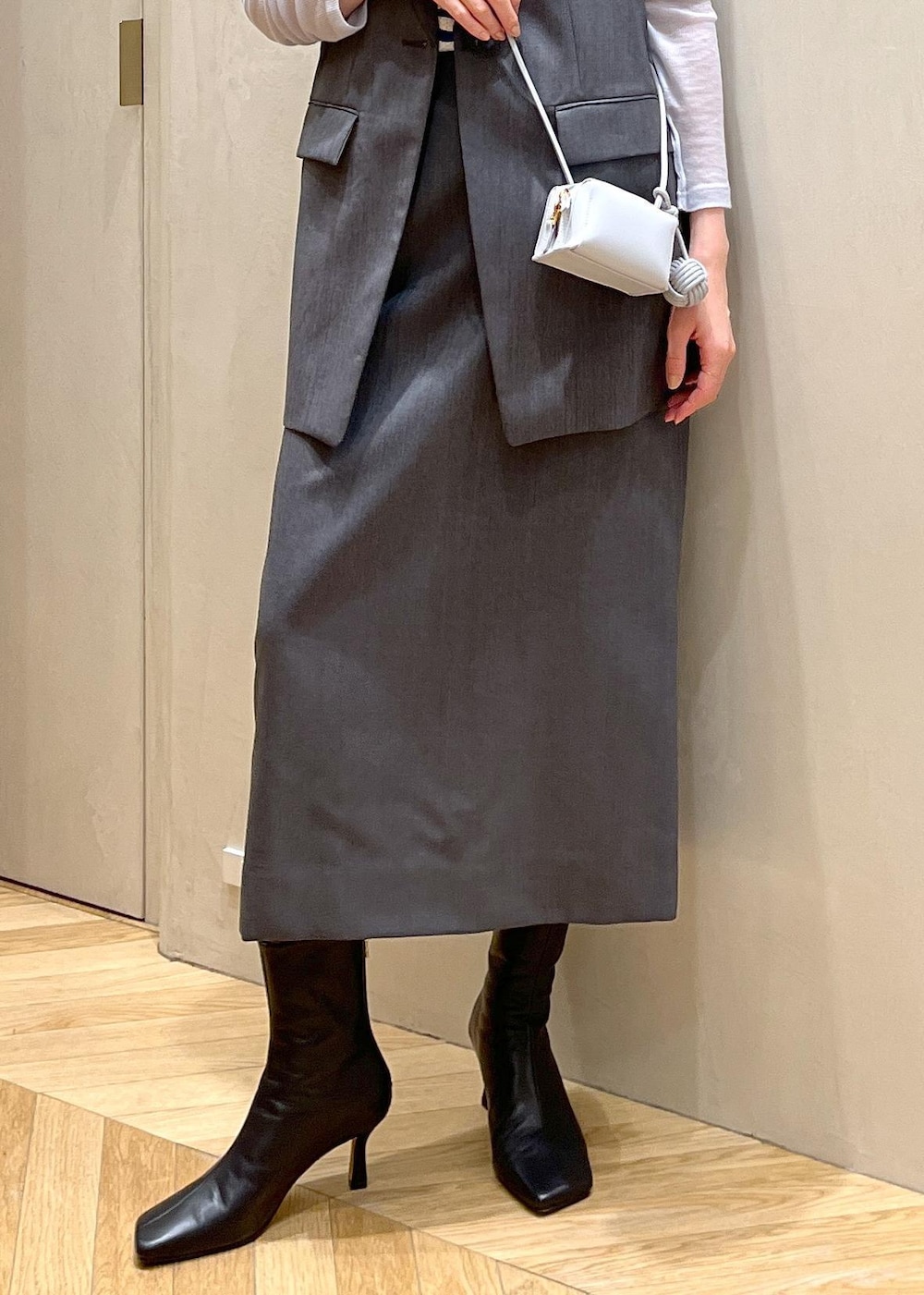 ブラック系のブーツ、ブルー系のショルダーバッグ、グレー系のベストを着用したレディースの秋コーディネートの6枚目の写真