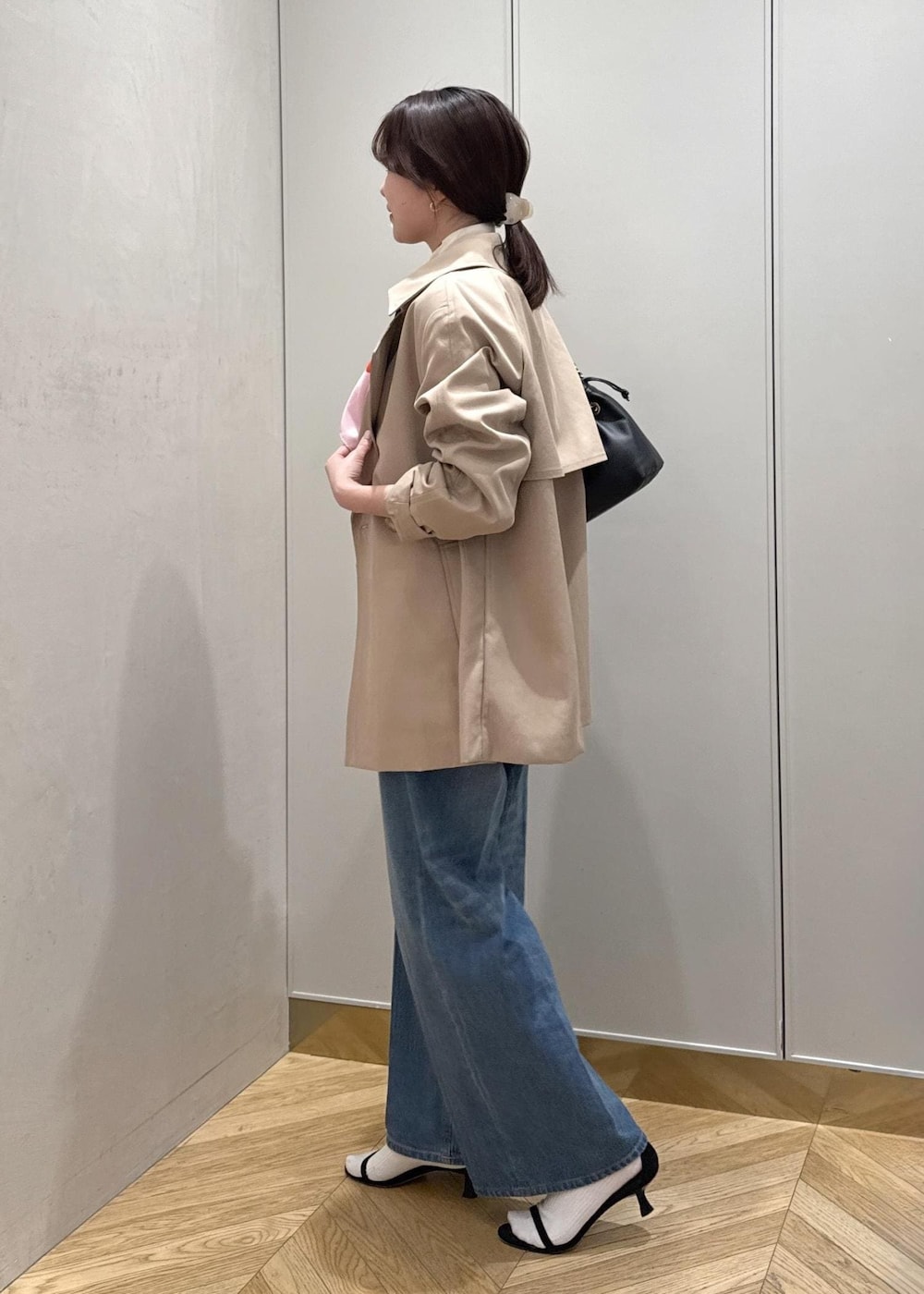 ブラック系のハンドバッグ、ホワイト系のニット/セーター、ブルー系のデニムパンツを着用したレディースの春コーディネートの3枚目の写真