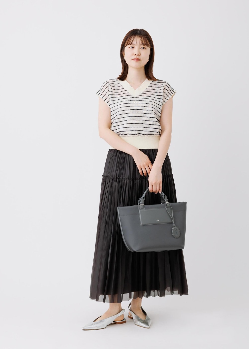 ブラック系のスカート、ホワイト系のニット/セーター、グレー系のトートバッグを着用したレディースの春コーディネートの3枚目の写真