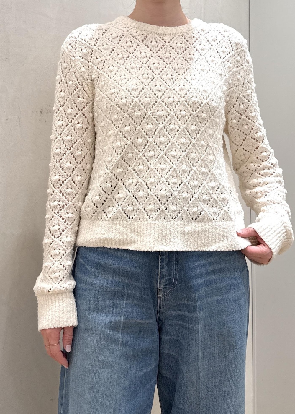 ブラック系のハンドバッグ、ホワイト系のニット/セーター、ブルー系のデニムパンツを着用したレディースの春コーディネートの7枚目の写真