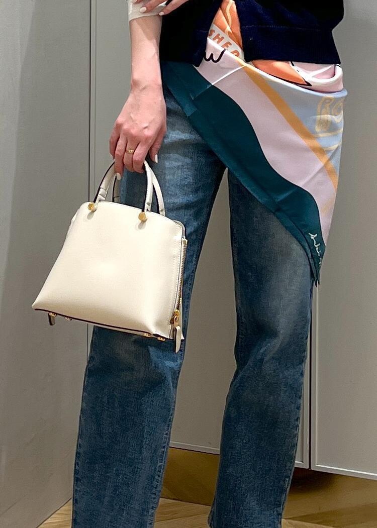 ホワイト系のハンドバッグ、シルバー系のパンプス、ブルー系のニット/セーターを着用したレディースの冬コーディネートの7枚目の写真