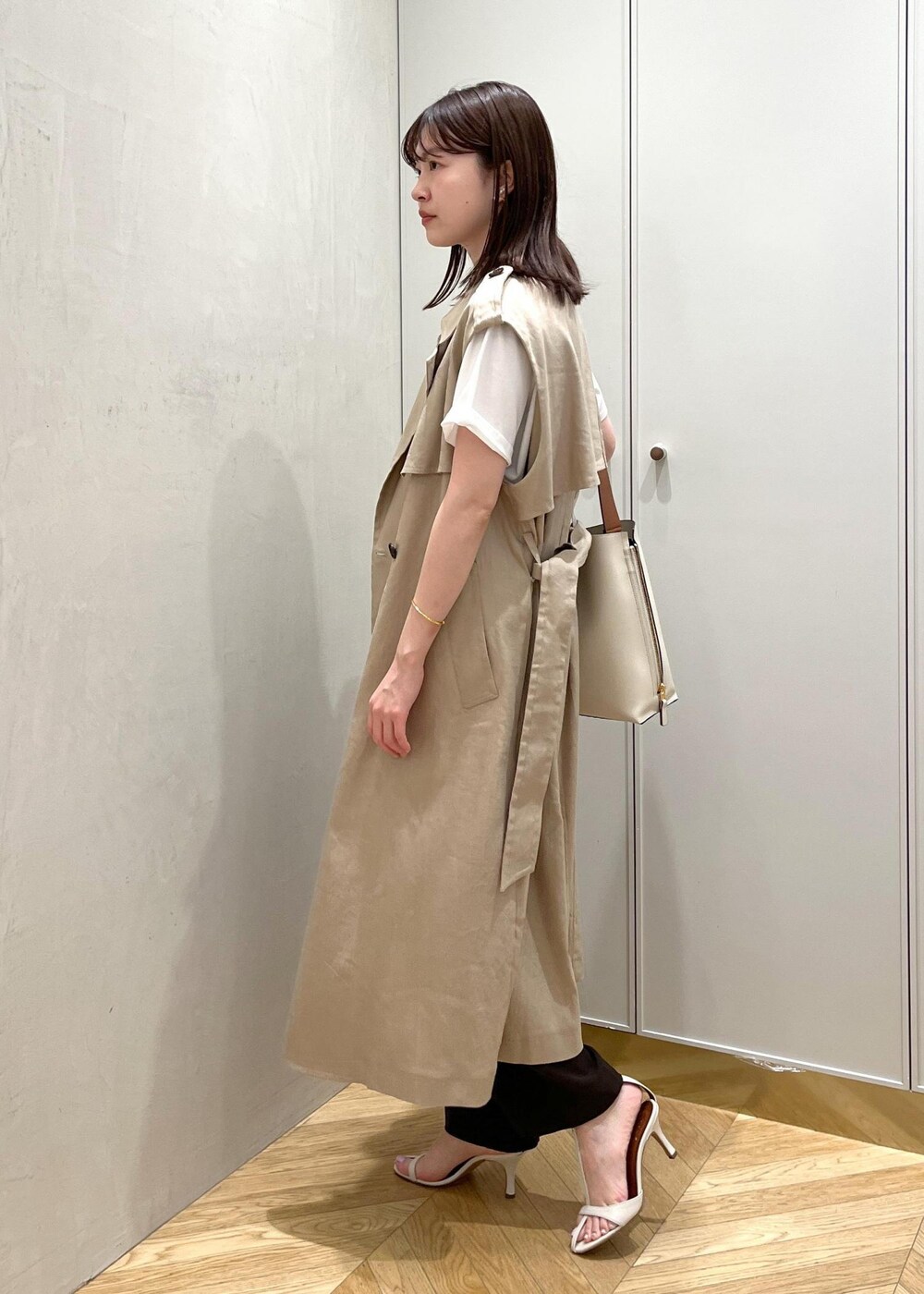 ホワイト系のサンダル、ベージュ系のベスト、ホワイト系のTシャツ/カットソーを着用したレディースの春コーディネートの2枚目の写真