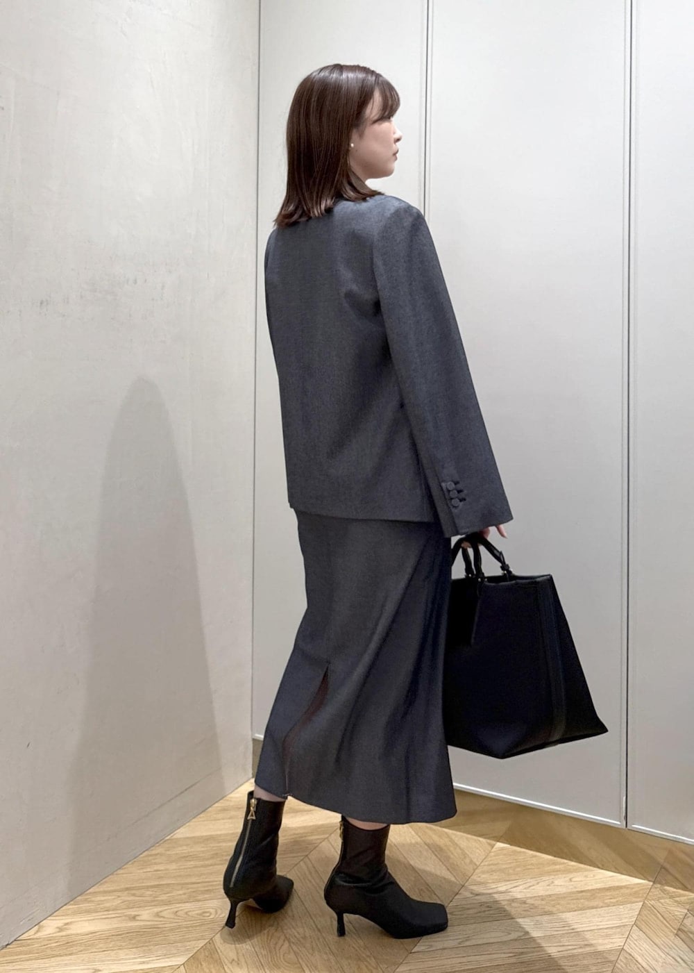 ブラック系のトートバッグ、ブルー系のテーラードジャケット、ブルー系のスカートを着用したレディースの冬コーディネートの3枚目の写真