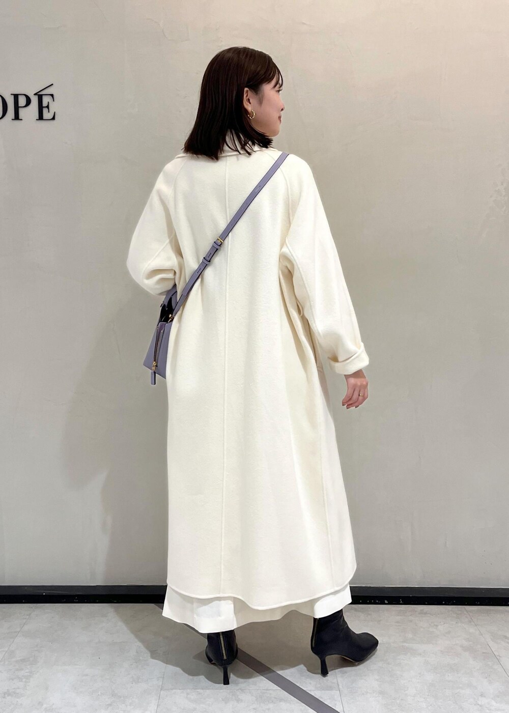 ブラック系のブーツ、ホワイト系のチェスターコート、ホワイト系のスカートを着用したレディースの秋コーディネートの3枚目の写真