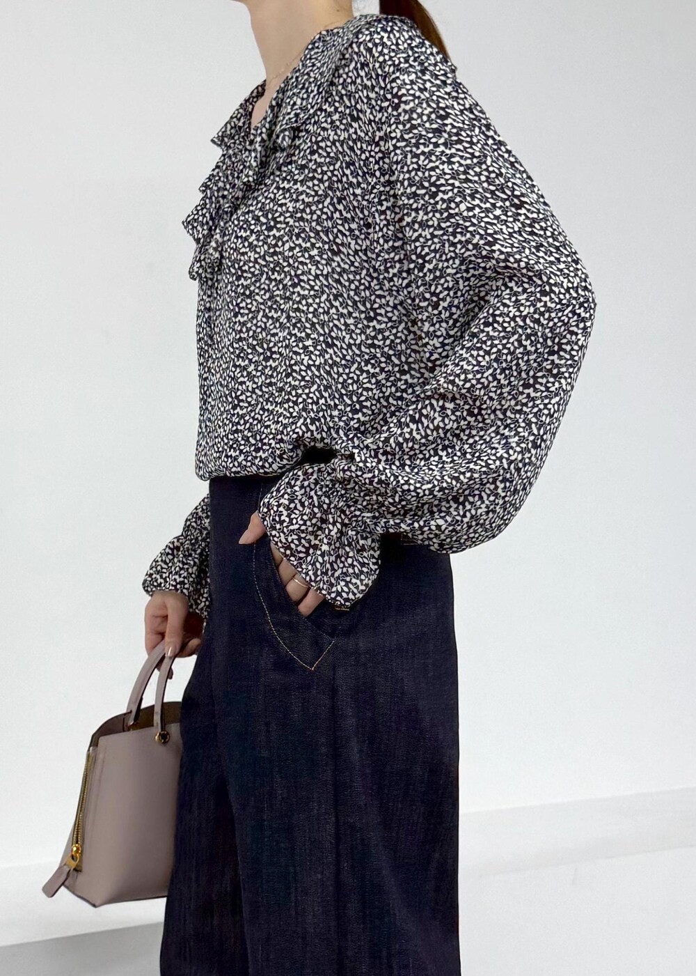 グレー系のハンドバッグ、ブラウン系のブーツ、ブルー系のデニムパンツを着用したレディースの秋コーディネートの6枚目の写真