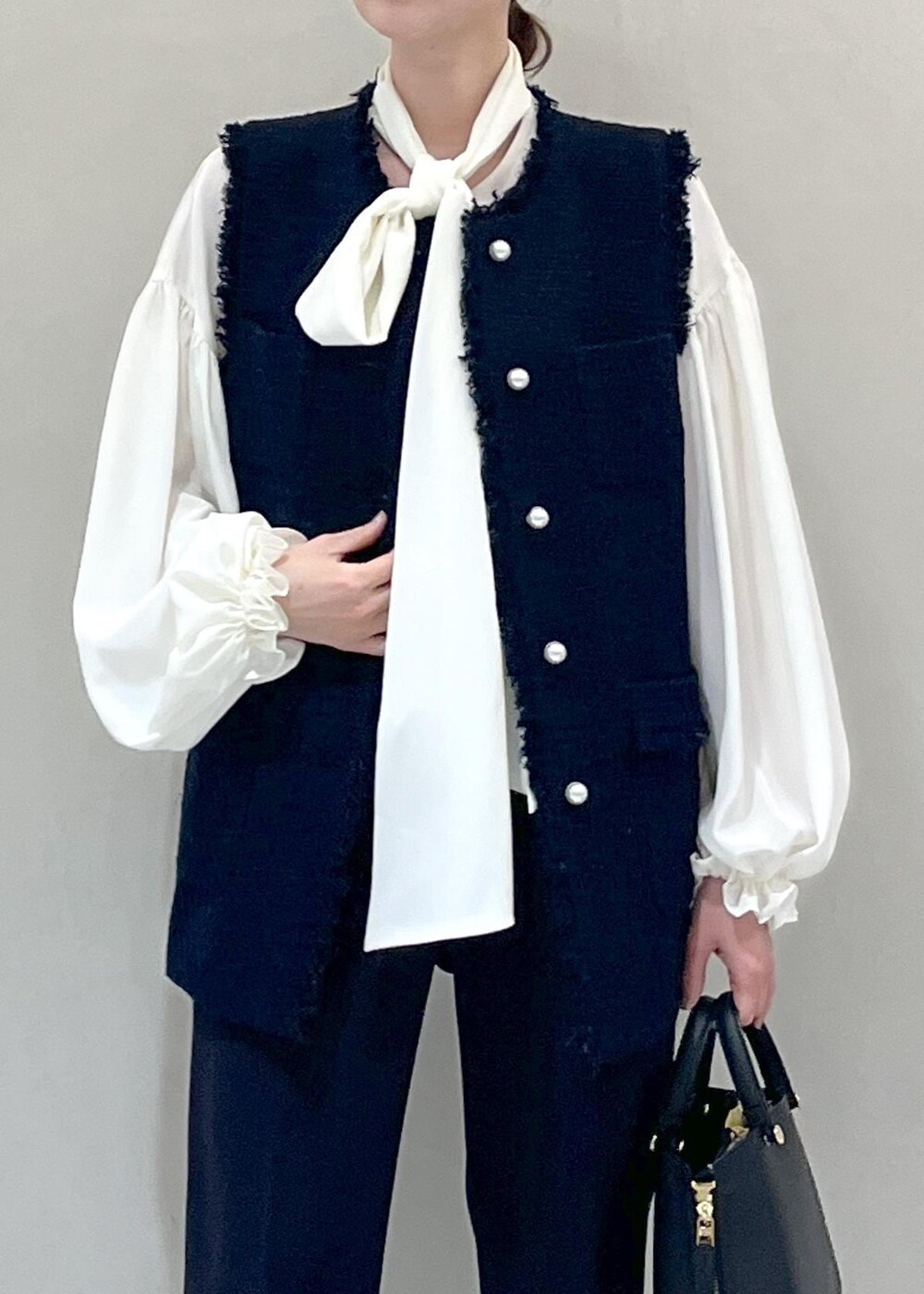 ブラック系のパンプス、ブラック系のハンドバッグ、ホワイト系のシャツ/ブラウスを着用したレディースの冬コーディネートの6枚目の写真