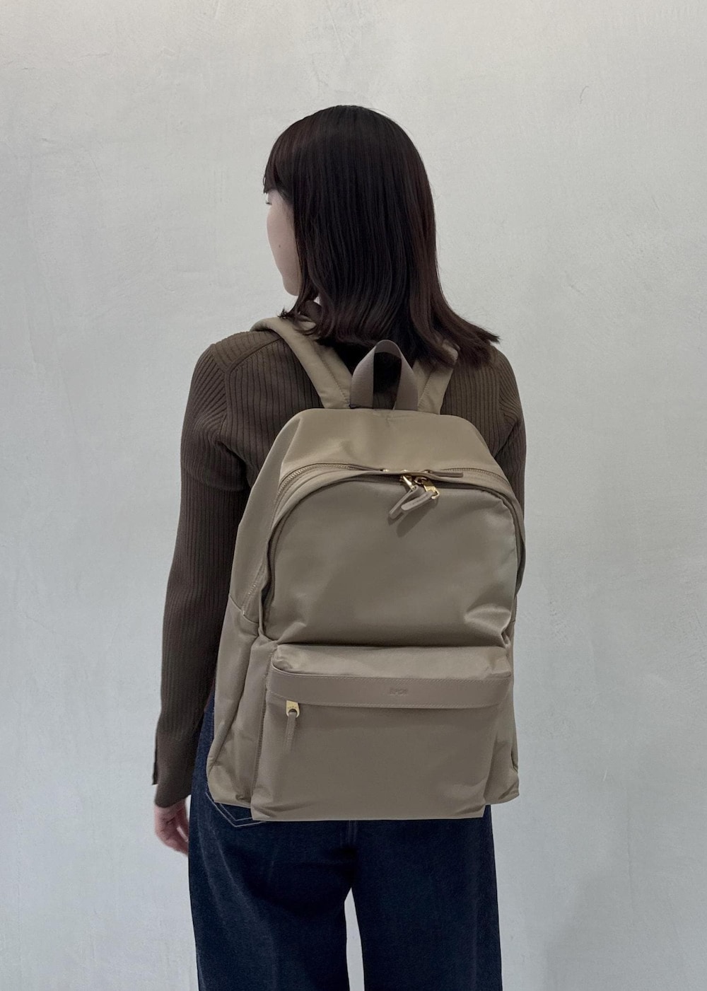 ベージュ系のバックパック/リュック、ブルー系のデニムパンツ、ブラウン系のカーディガン/ボレロを着用したレディースの秋コーディネートの9枚目の写真