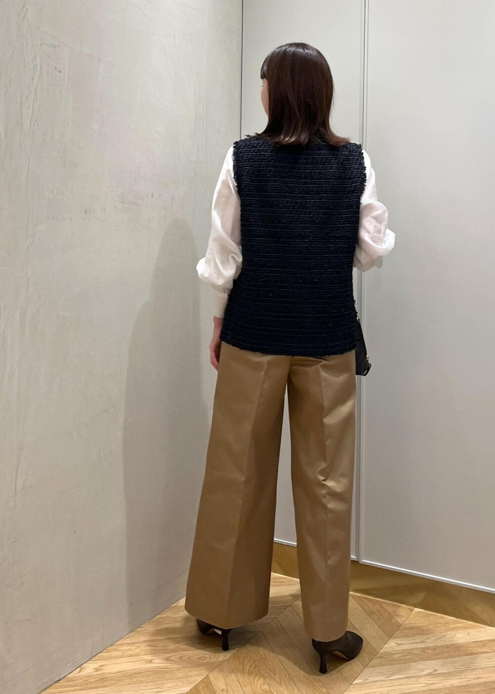 ブラック系のブーツ、ホワイト系のシャツ/ブラウス、ブルー系のベストを着用したレディースの秋コーディネートの3枚目の写真