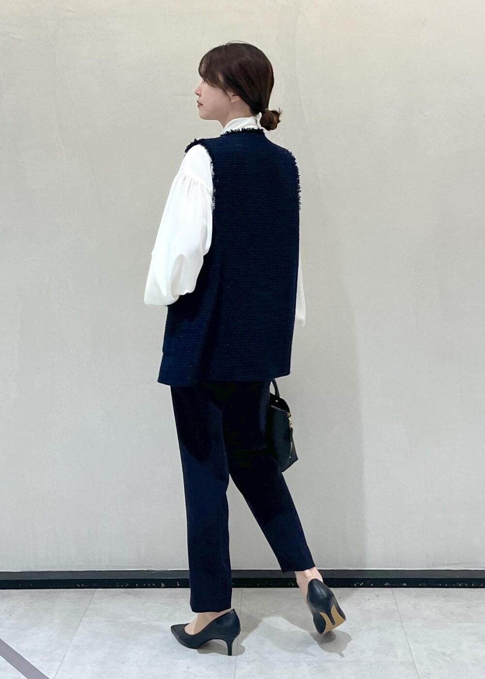 ブラック系のパンプス、ブラック系のハンドバッグ、ホワイト系のシャツ/ブラウスを着用したレディースの冬コーディネートの3枚目の写真