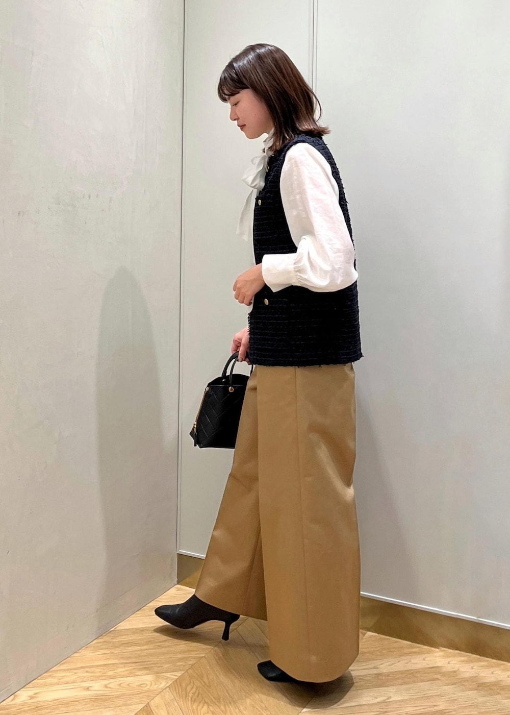 ブラック系のブーツ、ホワイト系のシャツ/ブラウス、ブルー系のベストを着用したレディースの秋コーディネートの2枚目の写真