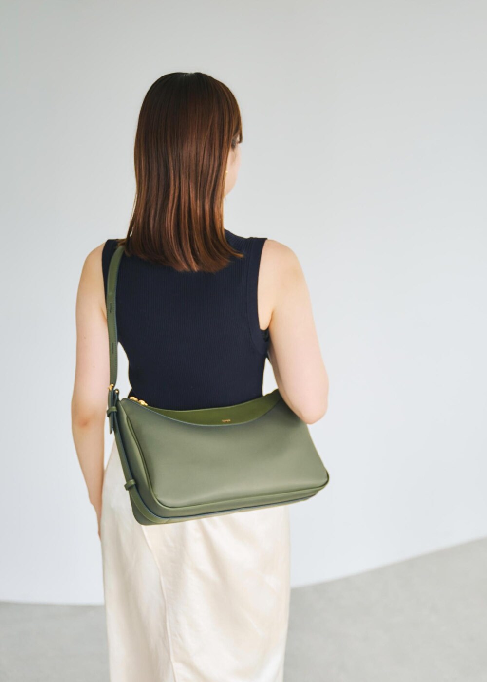 ブルー系のニット/セーター、グリーン系のハンドバッグ、ホワイト系のスカートを着用したレディースの春コーディネートの6枚目の写真