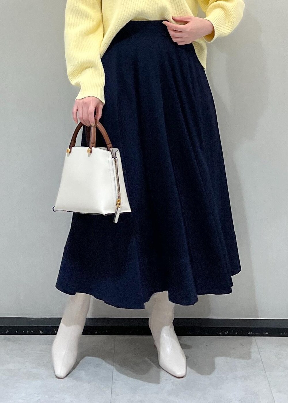 ホワイト系のハンドバッグ、ホワイト系のブーツ、ブルー系のスカートを着用したレディースの冬コーディネートの5枚目の写真