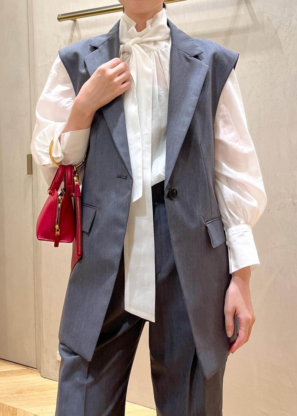 レッド系のパンプス、グレー系のベスト、グレー系のその他パンツを着用したレディースの秋コーディネートの4枚目の写真