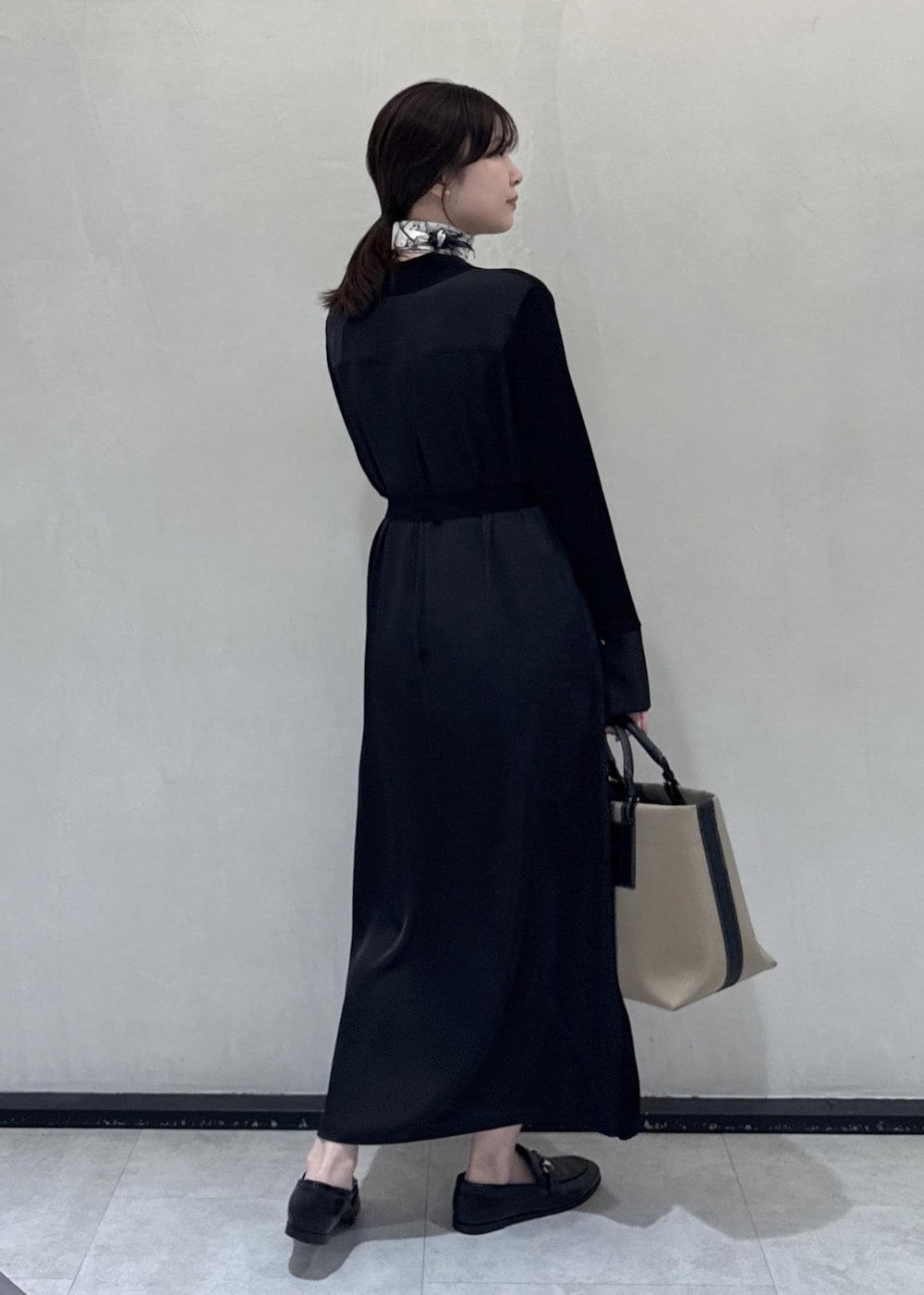 ブラック系のローファー、ベージュ系のハンドバッグ、ブラック系のワンピースを着用したレディースの秋コーディネートの3枚目の写真