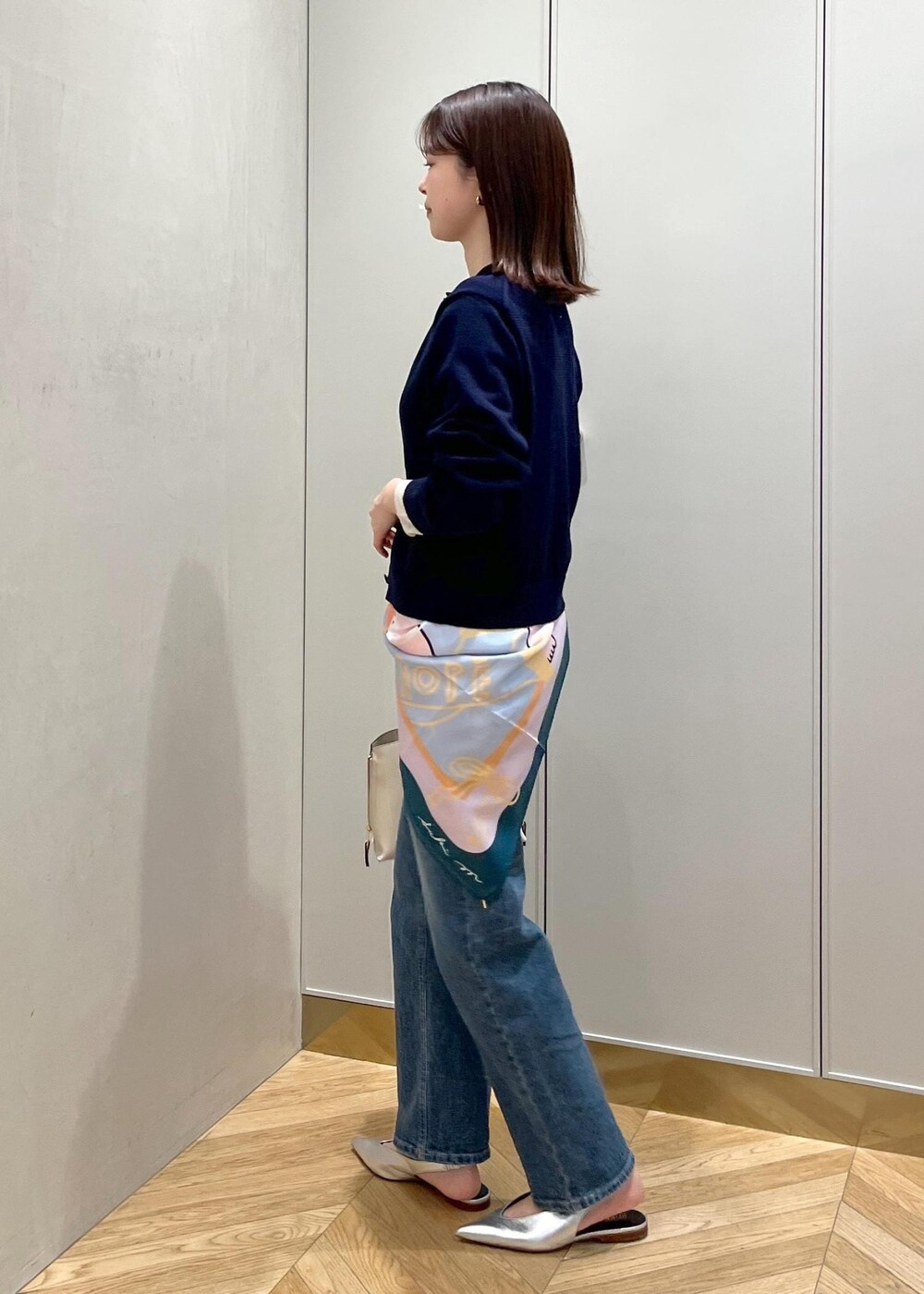 ホワイト系のハンドバッグ、シルバー系のパンプス、ブルー系のニット/セーターを着用したレディースの冬コーディネートの2枚目の写真