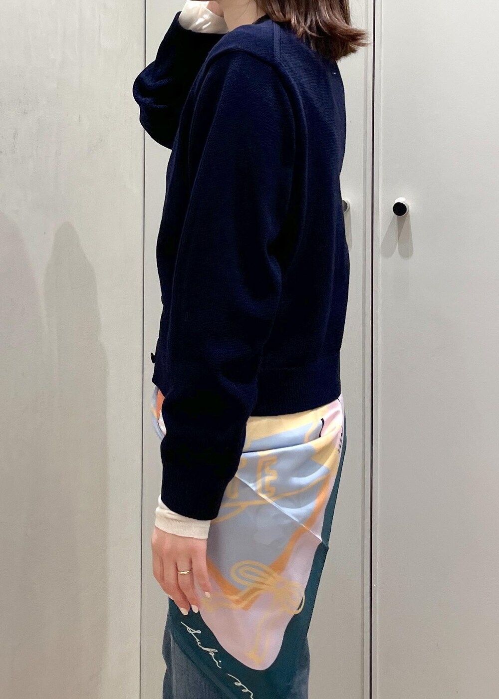 ホワイト系のハンドバッグ、シルバー系のパンプス、ブルー系のニット/セーターを着用したレディースの冬コーディネートの5枚目の写真