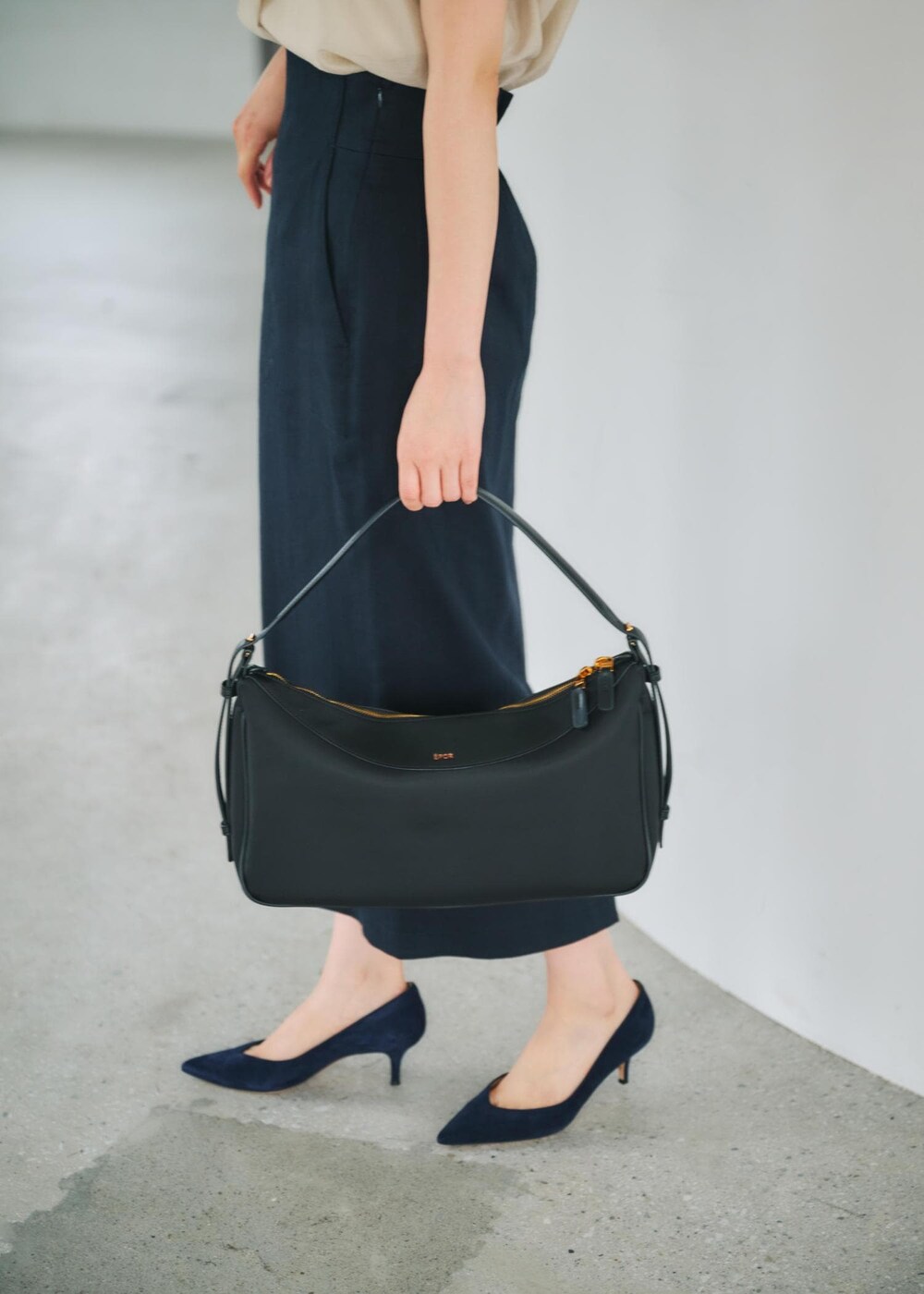 ブルー系のスカート、ブラック系のハンドバッグ、ベージュ系のシャツ/ブラウスを着用したレディースの春コーディネートの7枚目の写真