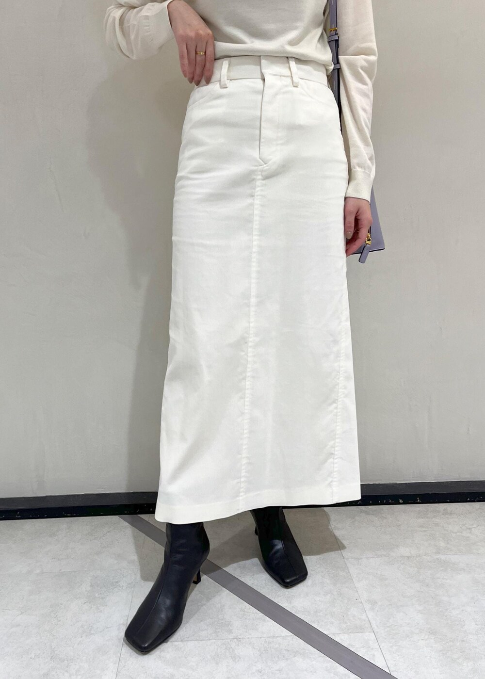 ブラック系のブーツ、ホワイト系のチェスターコート、ホワイト系のスカートを着用したレディースの秋コーディネートの8枚目の写真