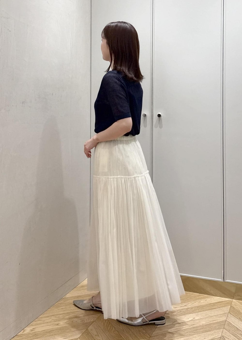 パープル系のハンドバッグ、ベージュ系のスカート、ブルー系のカーディガン/ボレロを着用したレディースの春コーディネートの3枚目の写真