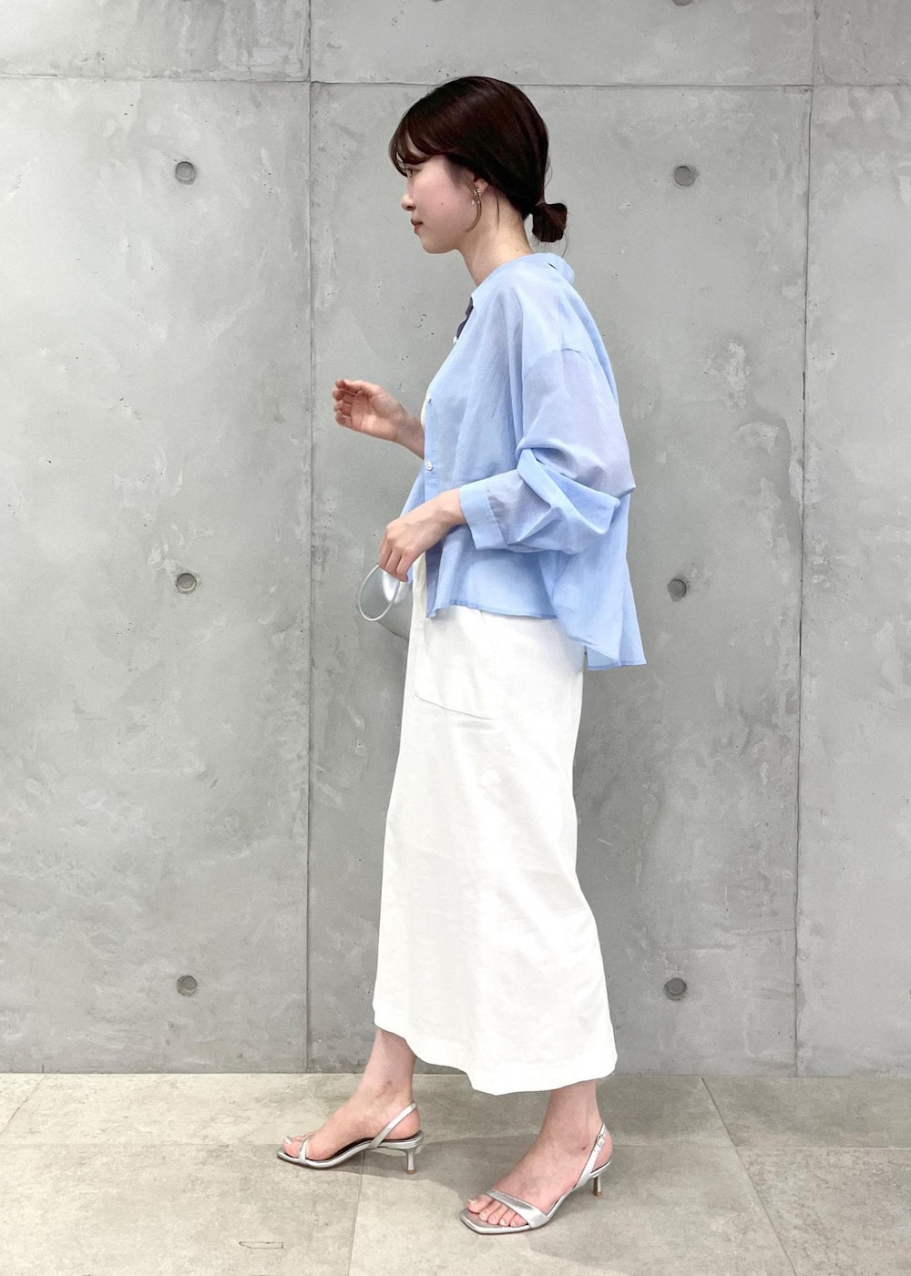 シルバー系のサンダル、ホワイト系のスカート、シルバー系のハンドバッグを着用したレディースの夏コーディネートの2枚目の写真
