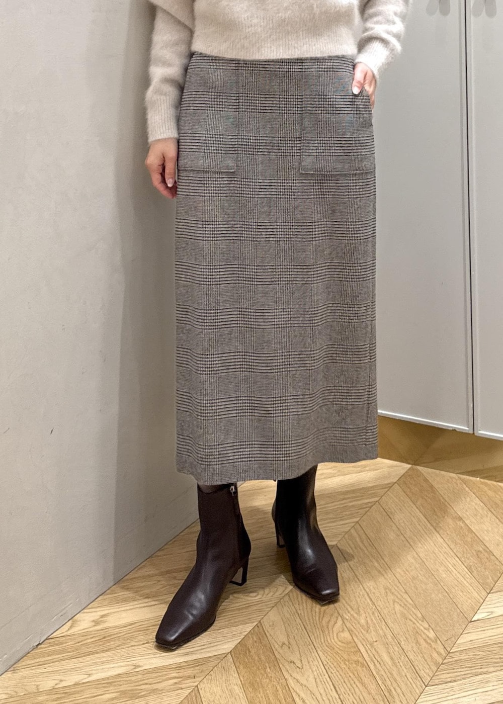 ブラウン系のブーツ、ブラウン系のハンドバッグ、ホワイト系のステンカラーコートを着用したレディースの秋コーディネートの6枚目の写真