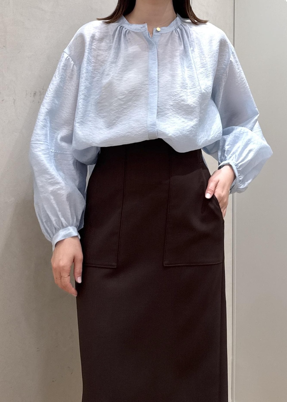 ブラウン系のスカート、ベージュ系のハンドバッグ、ブルー系のシャツ/ブラウスを着用したレディースの春コーディネートの4枚目の写真