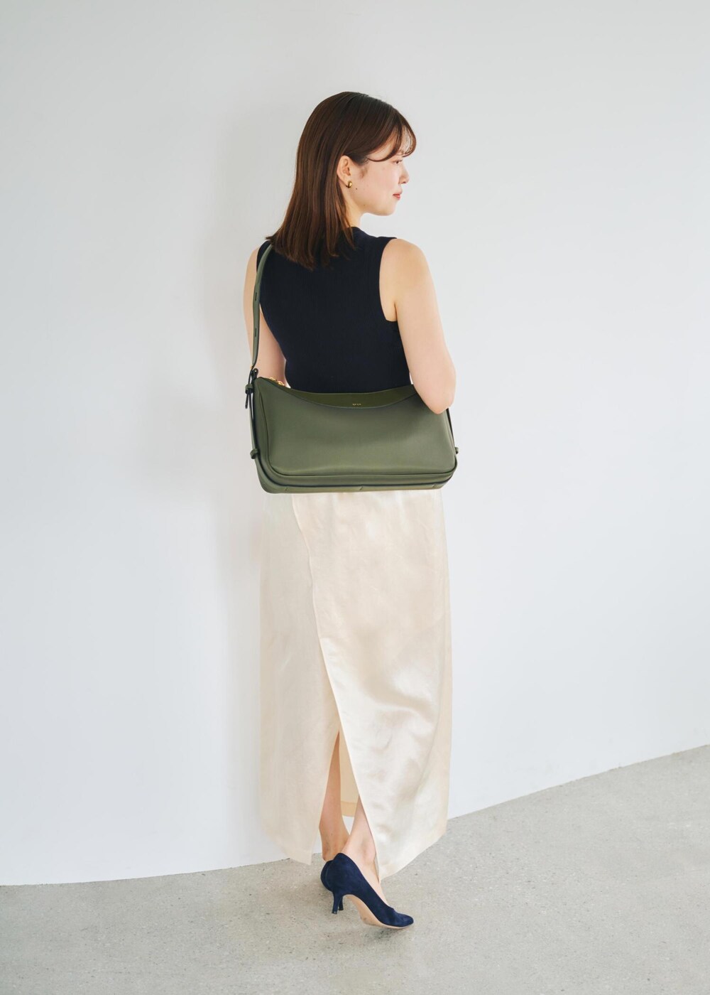 ブルー系のニット/セーター、グリーン系のハンドバッグ、ホワイト系のスカートを着用したレディースの春コーディネートの3枚目の写真